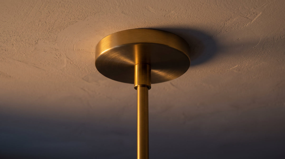 Rosace en laiton d'une suspension plaquée contre un plafond en enduit clair, refermée sur le point lumineux. Image