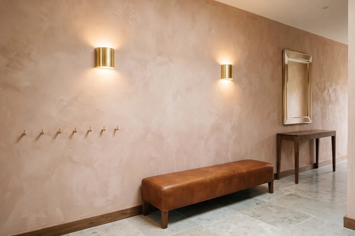 Éclairer une entrée : deux appliques murales identiques au-dessus d'une banquette de cuir, mur en badigeon terre cuite et sol de travertin. Image
