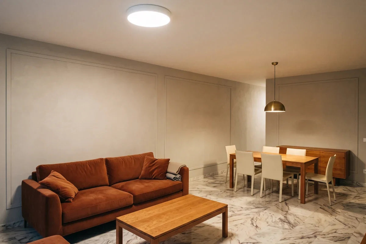 Plafonnier ou suspension : un plafonnier plaqué côté salon et une suspension au-dessus de la table, dans une même pièce ouverte. Image