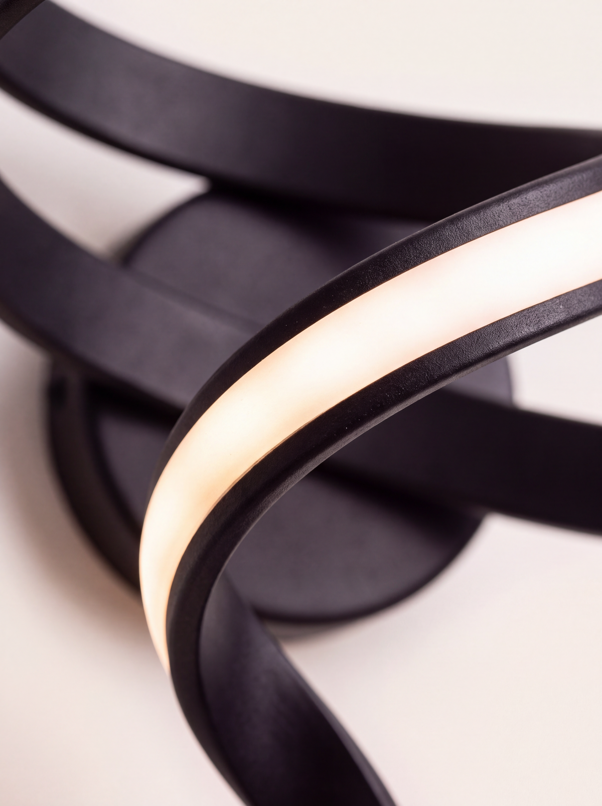 Détail du ruban de métal noir mat et de la bande de silicone translucide allumée de l'applique Blois