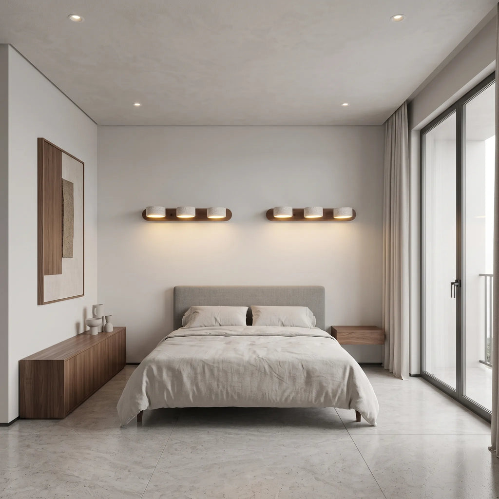 Applique murale 3 spots orientables Lumilarme au-dessus d'un lit, mur de travertin honé et tête de lit en daim caramel