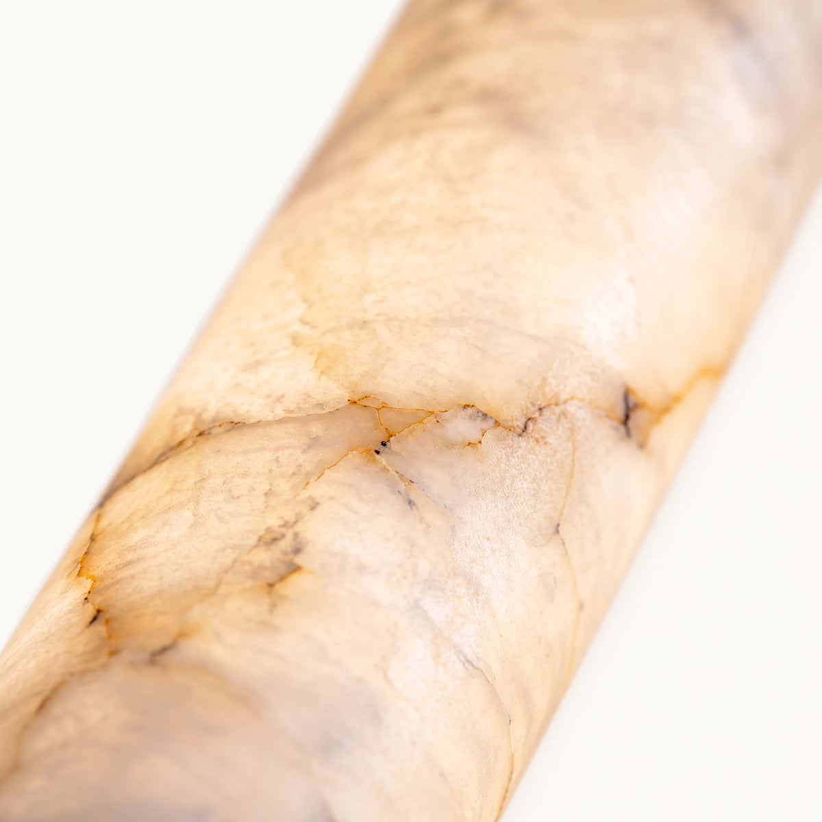 Détail de la pierre reconstituée du tube allongé, veines ocre et grises révélées par transparence