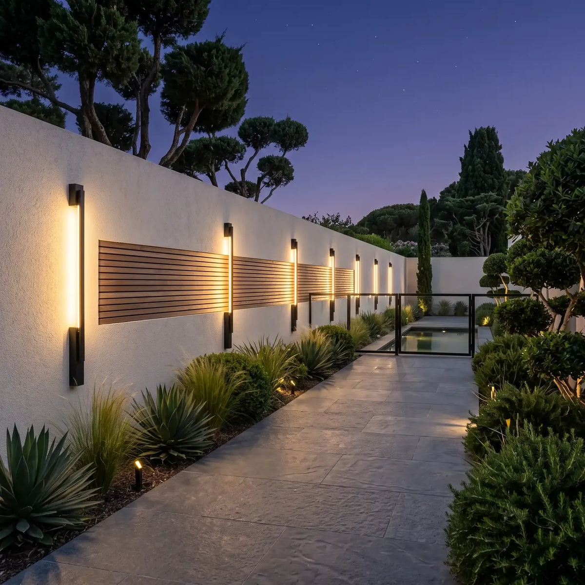 Série de tubes lumineux sur un long mur enduit bordant une allée de jardin méditerranéen