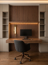 Applique murale longue dorée sur un mur de tasseaux au-dessus d'un bureau en bois