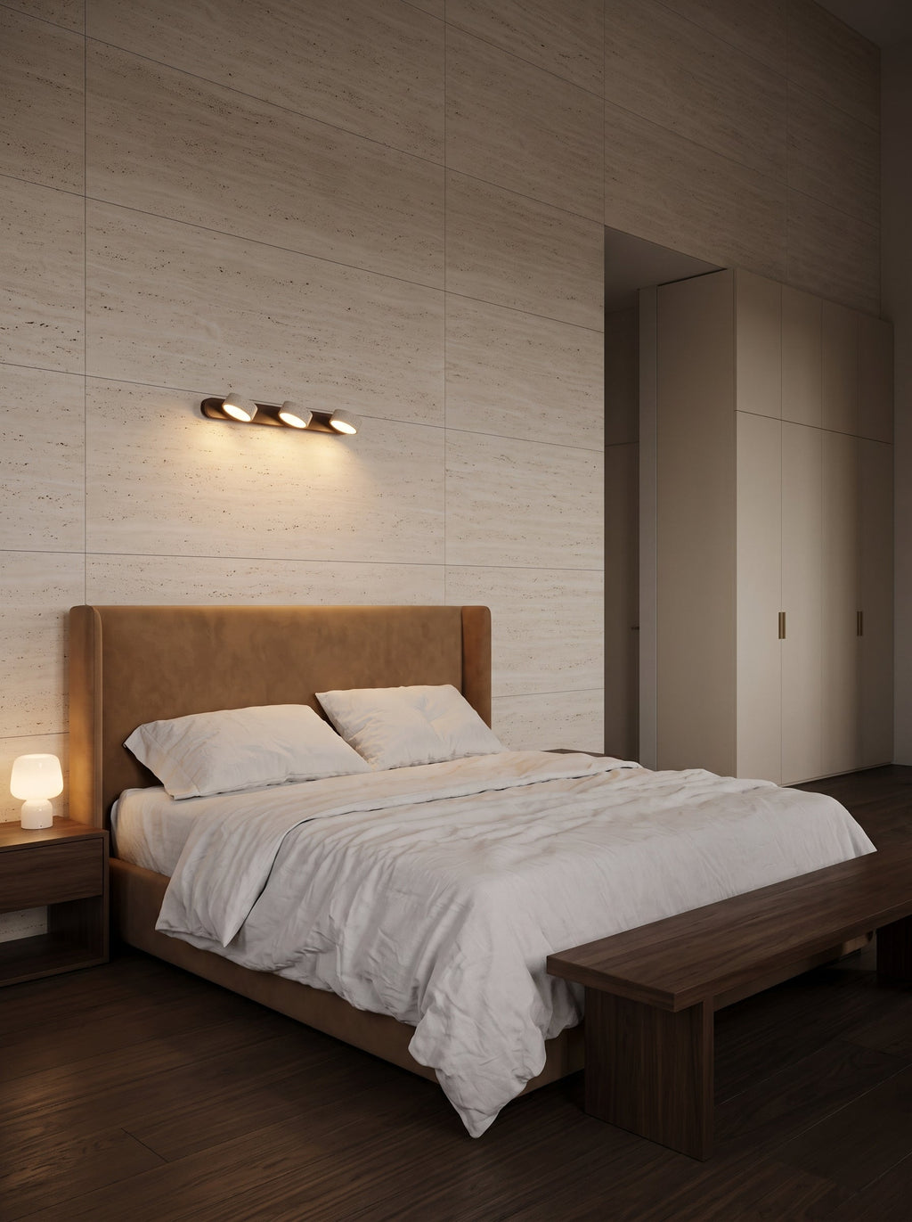 Applique murale 3 spots orientables Barbizon au-dessus d'un lit, mur de travertin honé et tête de lit en daim caramel