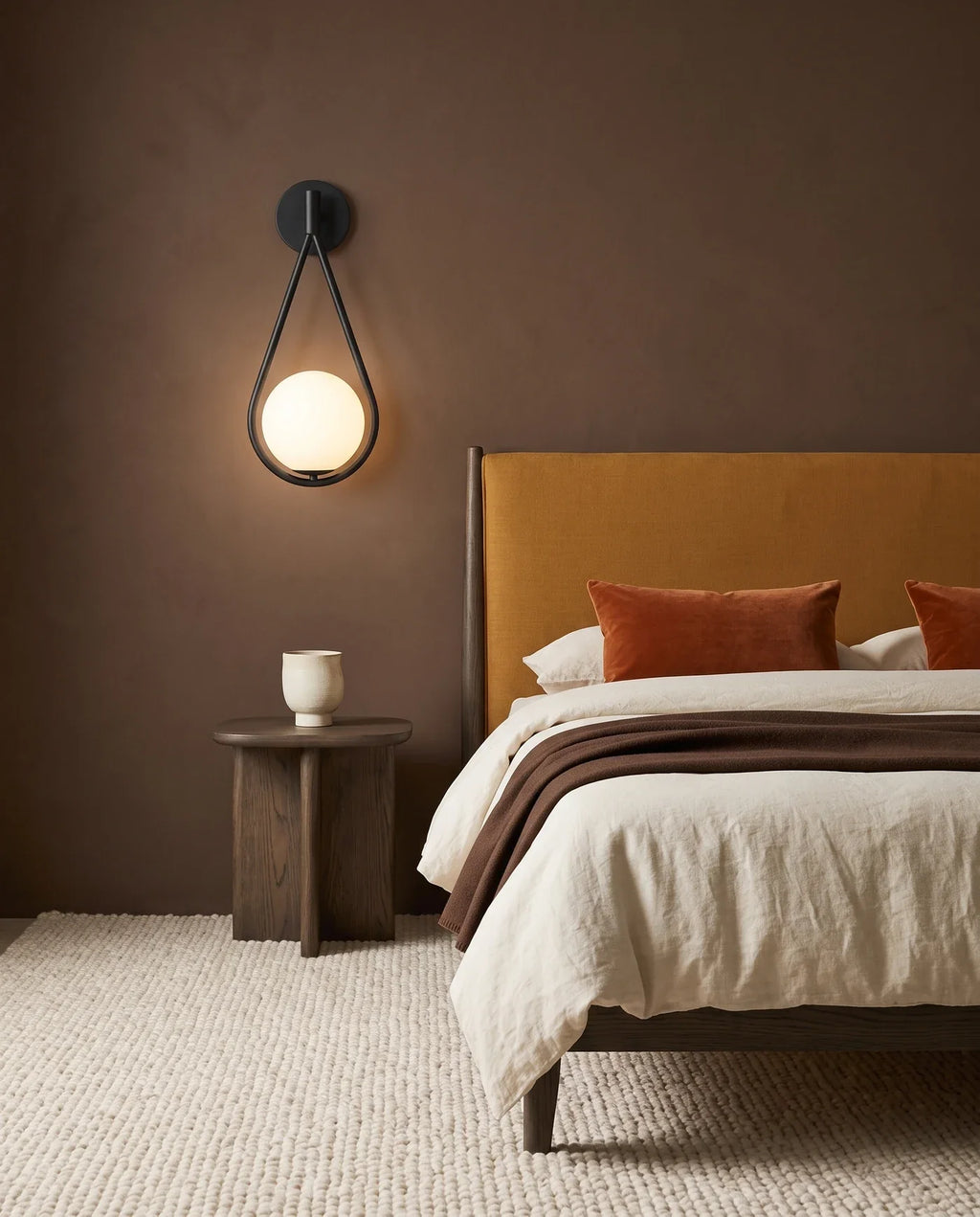 Applique murale à globe de verre opalin au-dessus d'un chevet de chambre