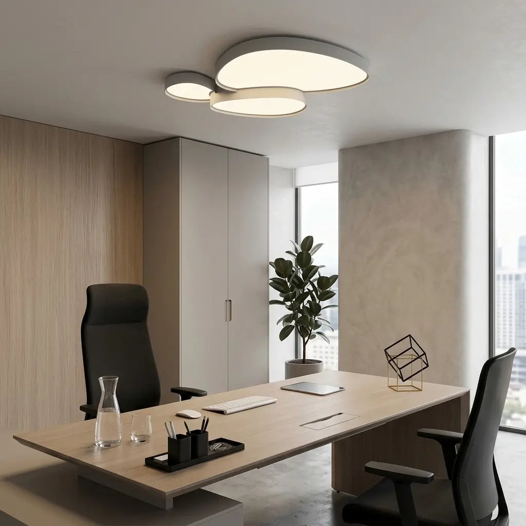 Plafonnier blanc à trois galets au plafond d'un bureau clair, au-dessus d'un plan de travail.