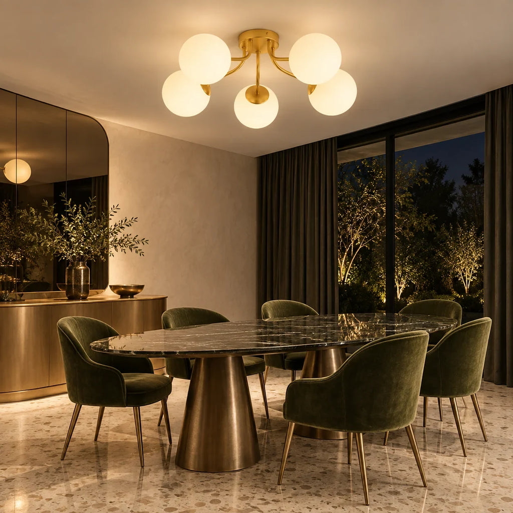 Cinq globes dorés allumés au-dessus d'une table ovale en marbre sombre et de fauteuils de velours vert