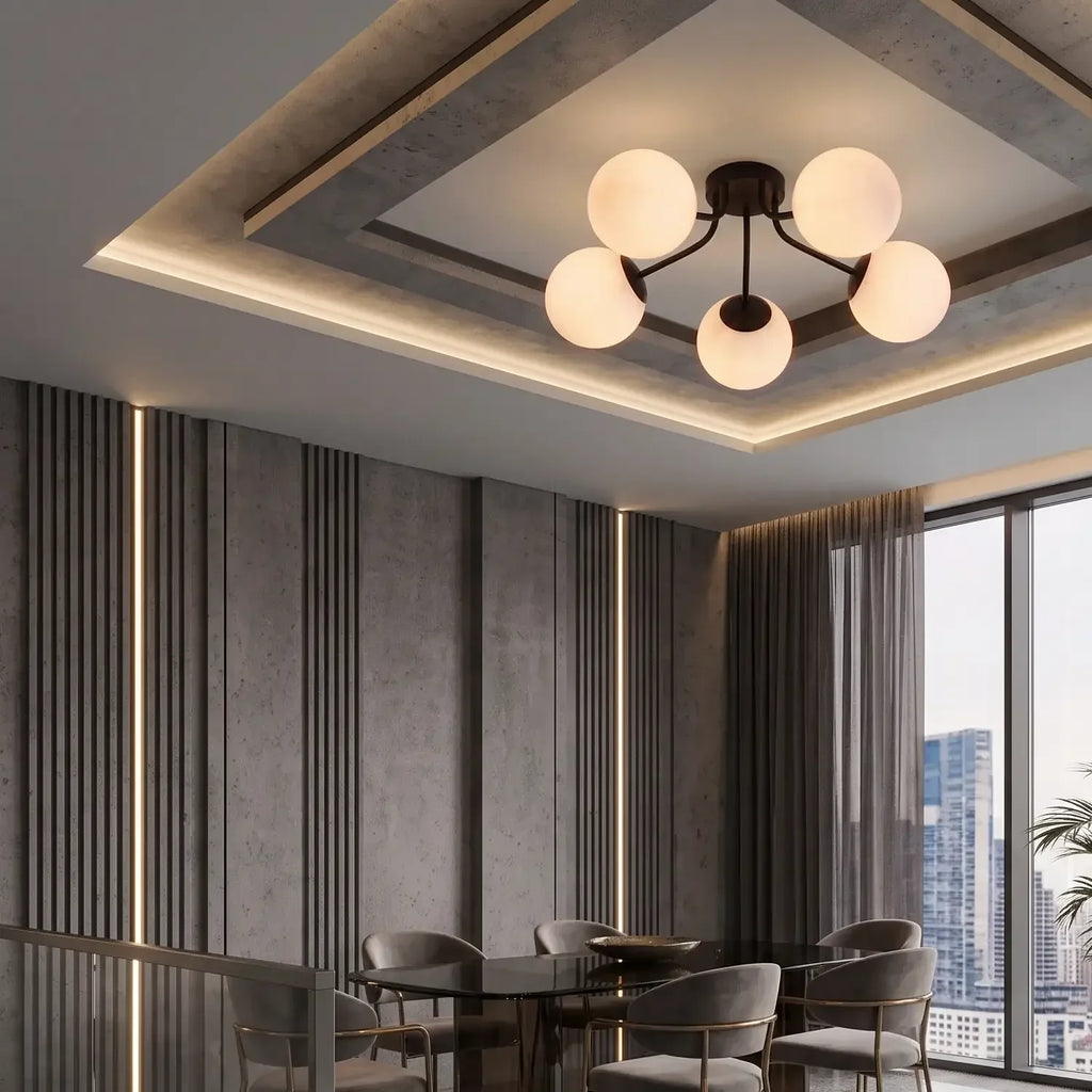 Cinq globes noir charbon allumés sous un faux plafond, au-dessus d'une table de verre fumé