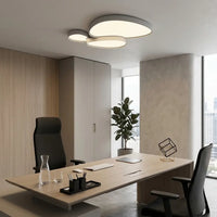 Plafonnier blanc à trois galets au plafond d'un bureau clair, au-dessus d'un plan de travail.