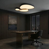 Plafonnier noir à trois galets au plafond d'un bureau, au-dessus d'une table de travail.