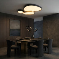 Plafonnier noir à trois galets au-dessus d'une table de salle à manger en bois sombre.