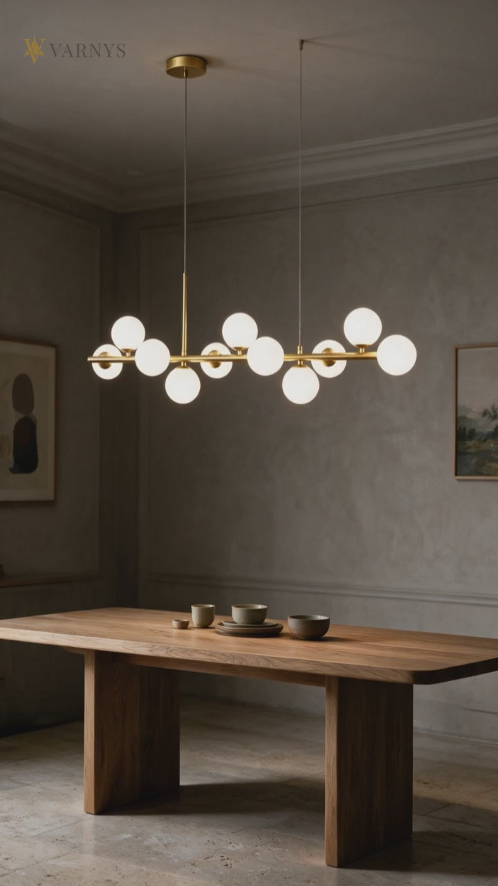 Suspension linéaire dorée à globes de verre opalin au-dessus d'une table de salle à manger en bois.