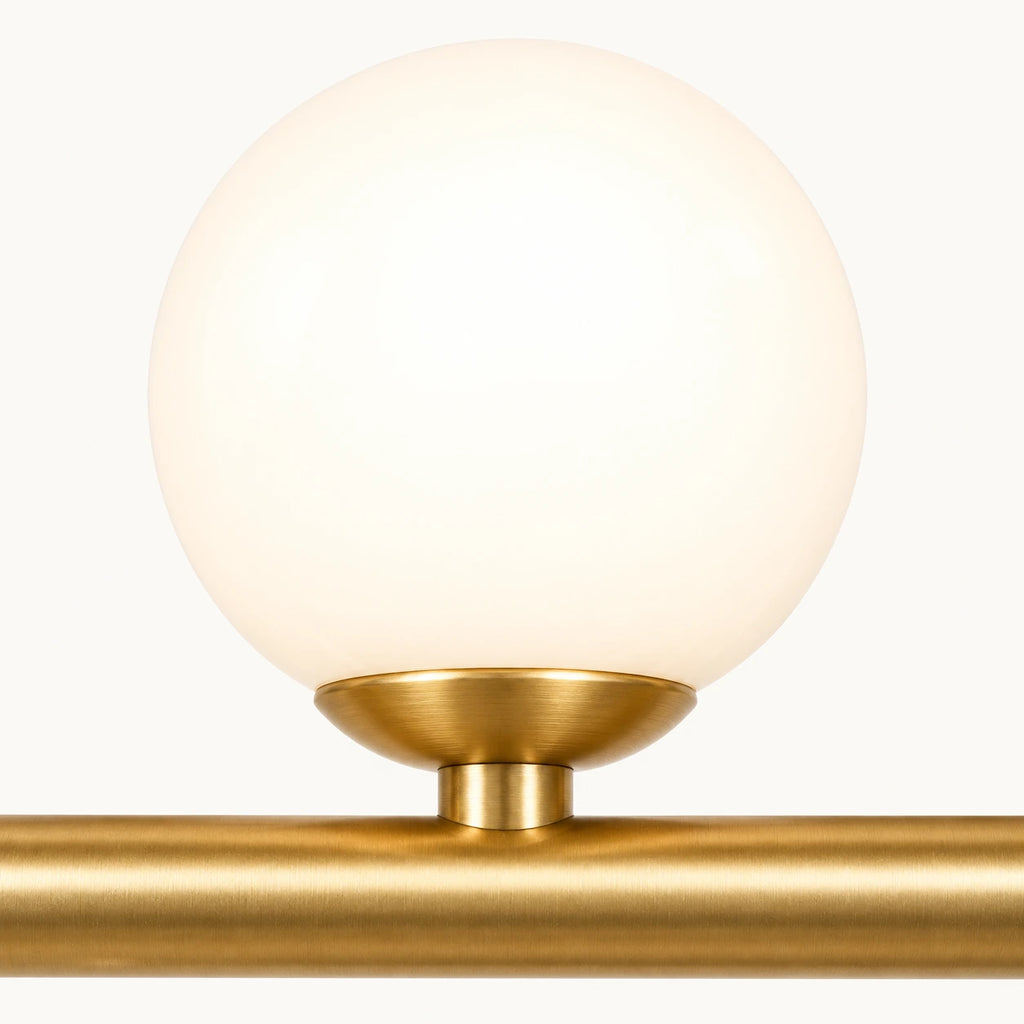 Détail d'un globe de verre opalin allumé et de sa bague doré satiné sur la barre de la suspension