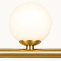 Détail d'un globe de verre opalin allumé et de sa bague doré satiné sur la barre de la suspension