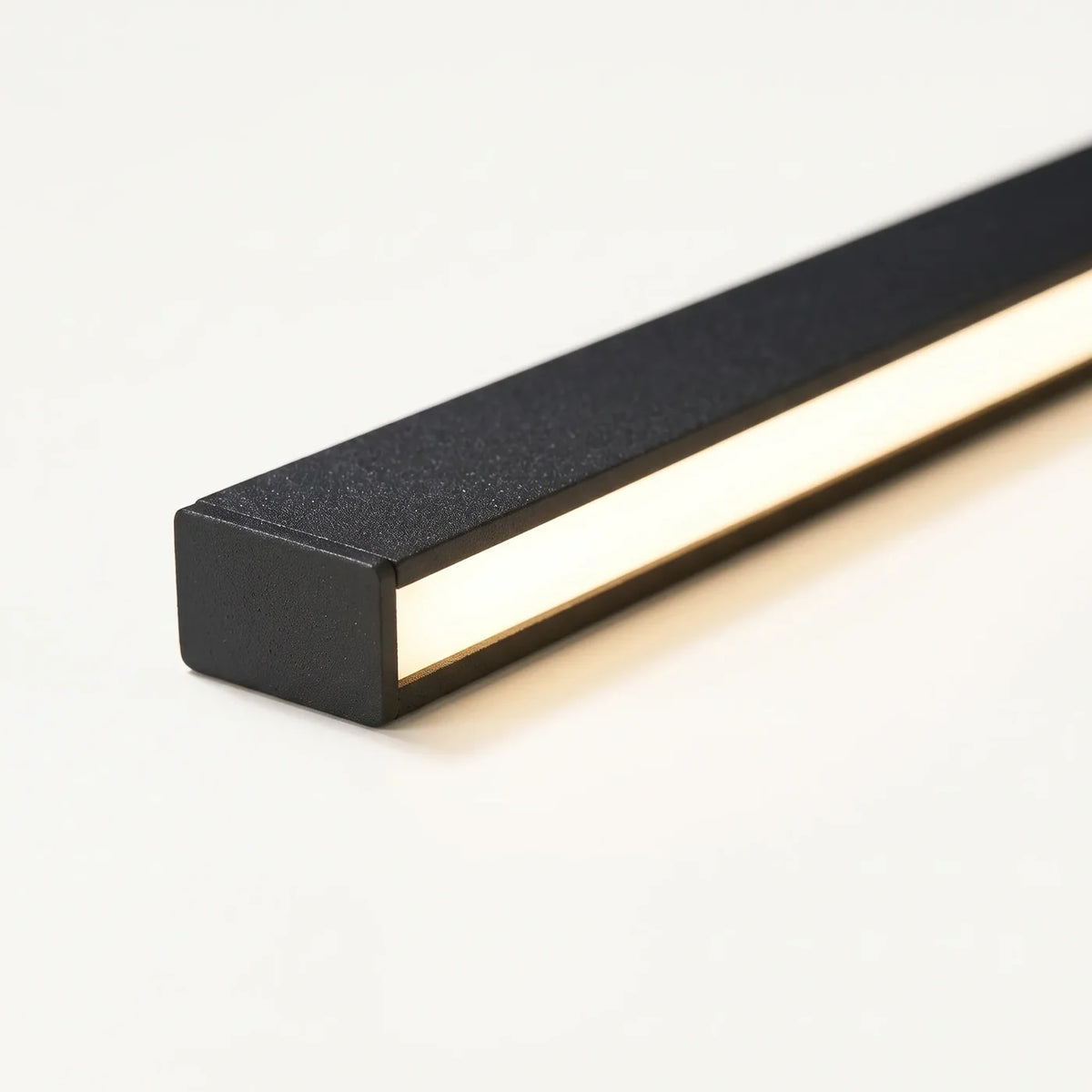 Macro d'une barre de métal noir à peinture texturée et de sa gorge LED allumée