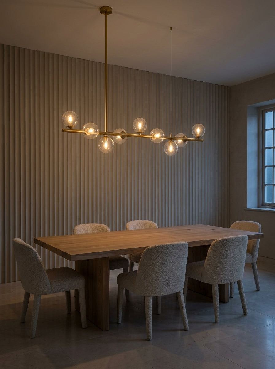 Barre doré satiné et globes de verre transparent au-dessus d'une table de salle à manger en chêne clair