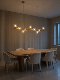 Barre doré satiné et globes de verre transparent au-dessus d'une table de salle à manger en chêne clair
