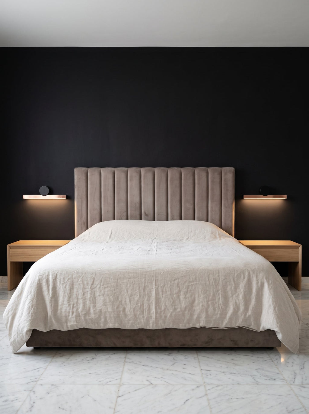 Barre lumineuse cuivrée au-dessus d'une tête de lit, mur noir mat et sol de marbre blanc